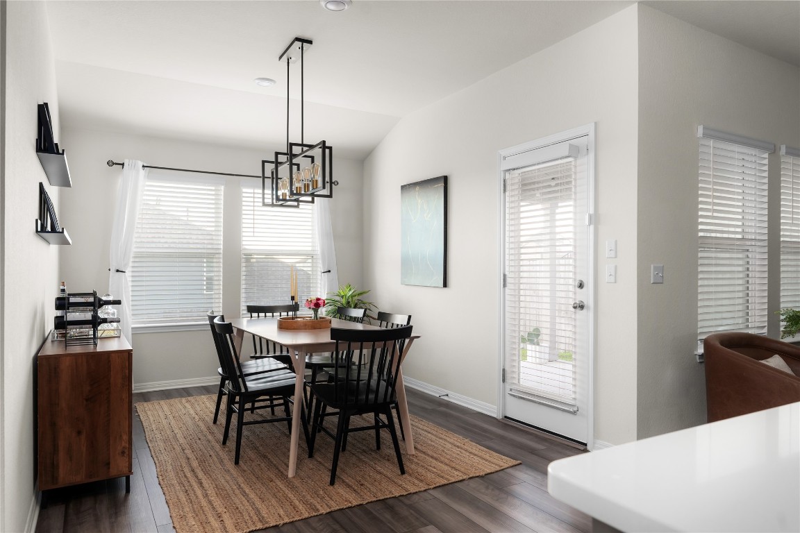 6511 Rounded Pebble Lane Buda, TX 78610 - Photo 5 of 25 Dining space featuring dark wood-type flooring, lofted ceiling, and a chandelier