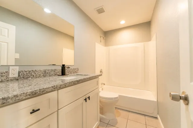 a bathroom with a granite countertop sink toilet and shower