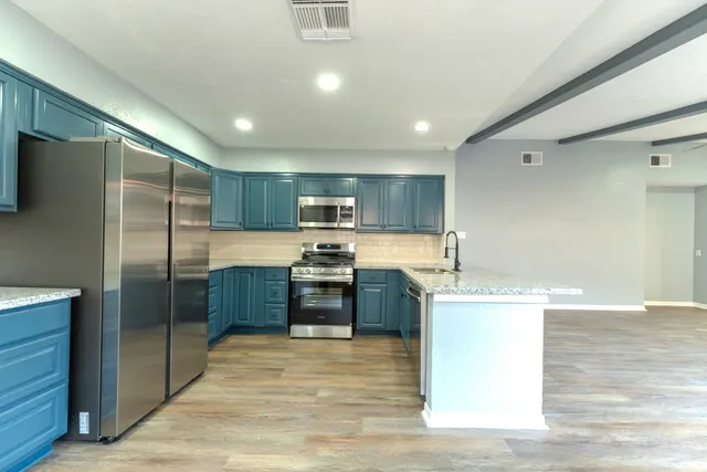 a open kitchen with stainless steel appliances kitchen island granite countertop a refrigerator and a sink