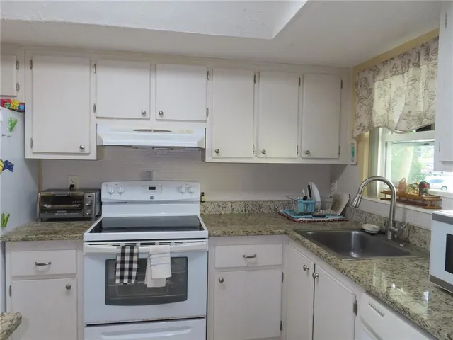 a kitchen with stainless steel appliances granite countertop white cabinets stove top oven and sink