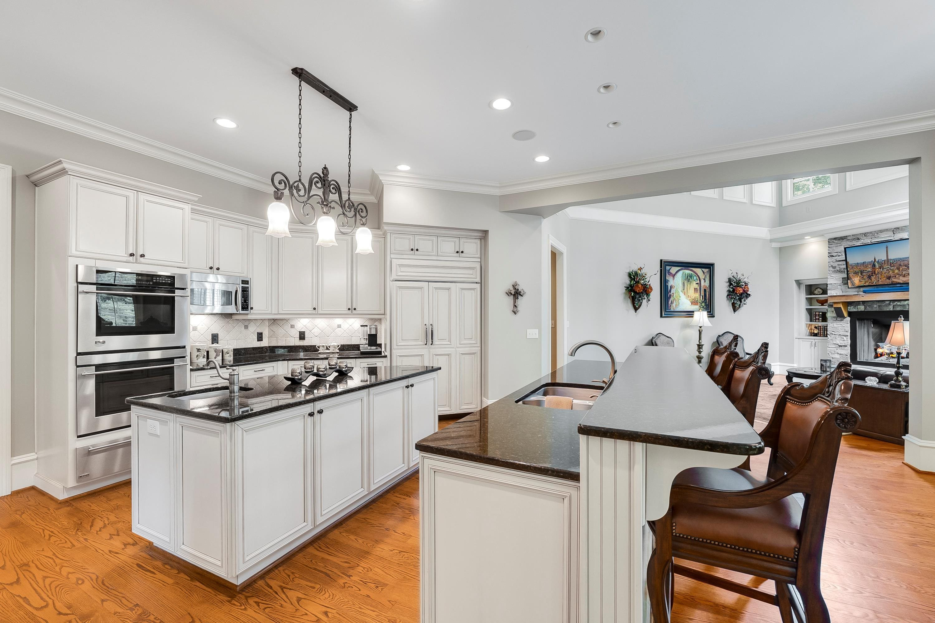 9712 Honeycutt Road Raleigh, NC 27614 - Photo 14 of 83 a kitchen with stainless steel appliances granite countertop a stove top oven a sink a dining table and chairs with wooden floor