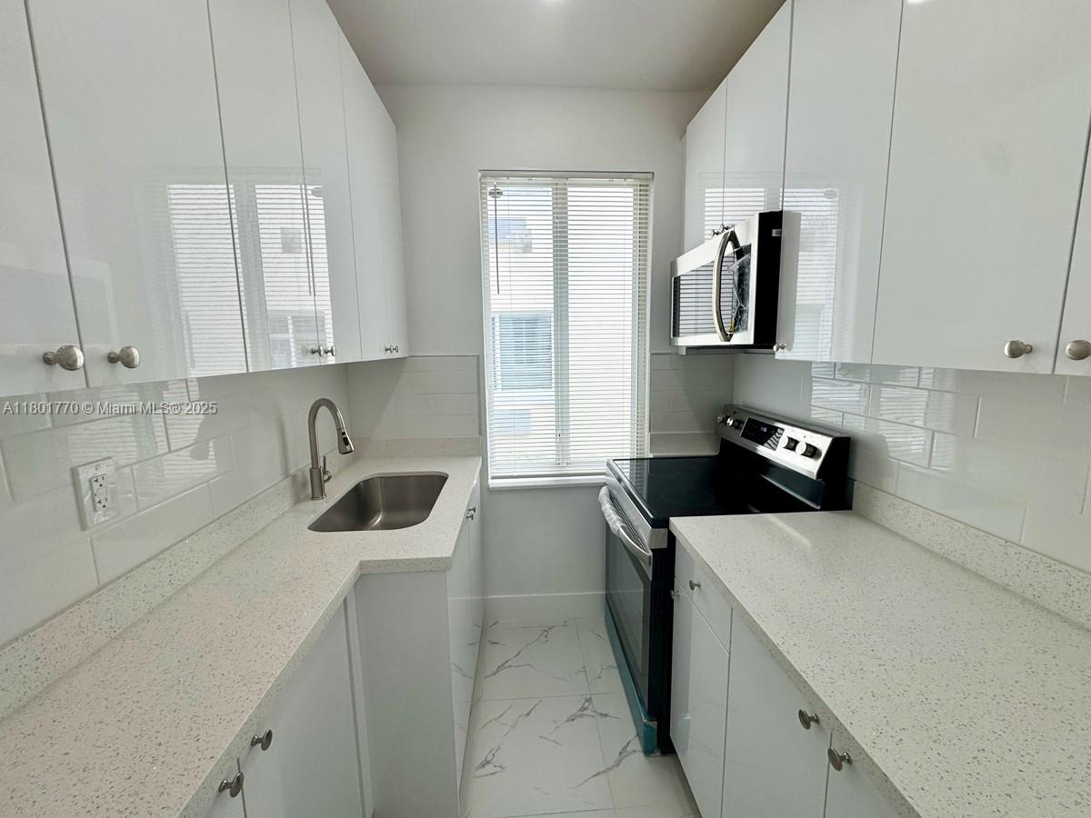 a kitchen with stainless steel appliances a sink a stove and refrigerator