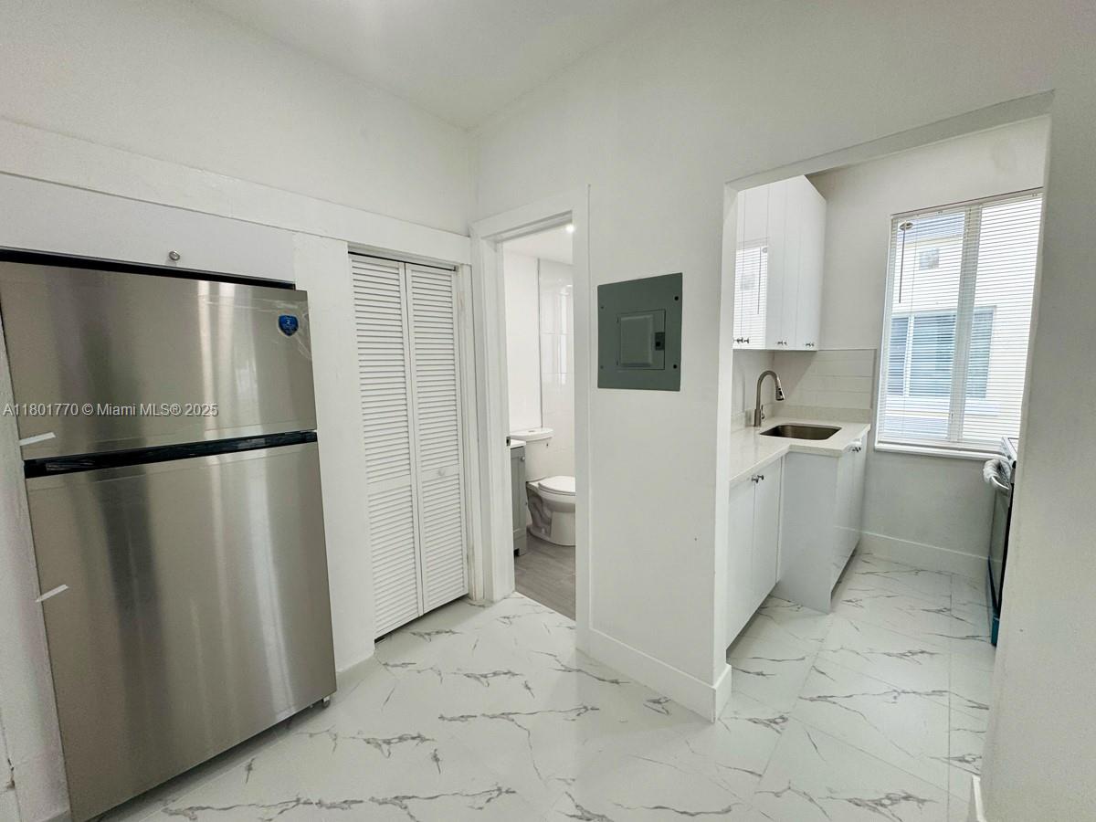 856 Southwest 6th Street, Unit 102 Miami, FL 33130 - Photo 4 of 9 a kitchen with a refrigerator and white cabinets