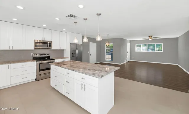 a kitchen with granite countertop a stove top oven a sink dishwasher and a refrigerator with wooden floor