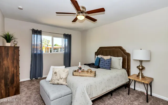 a bedroom with a bed a ceiling fan and a dresser