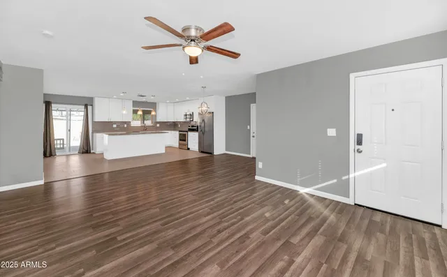 an empty room with wooden floor and a ceiling fan