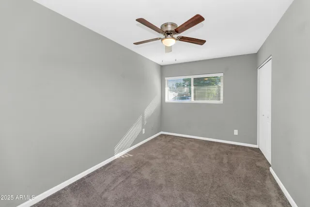 an empty room with a window and a fan