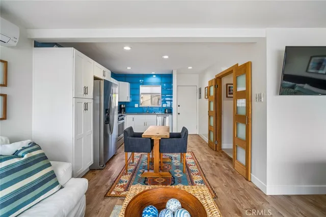 a living room with stainless steel appliances furniture wooden floor and a view of kitchen