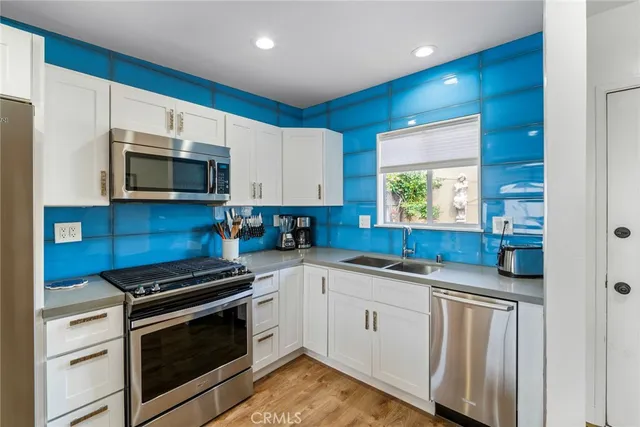 a kitchen with granite countertop a sink cabinets and stainless steel appliances