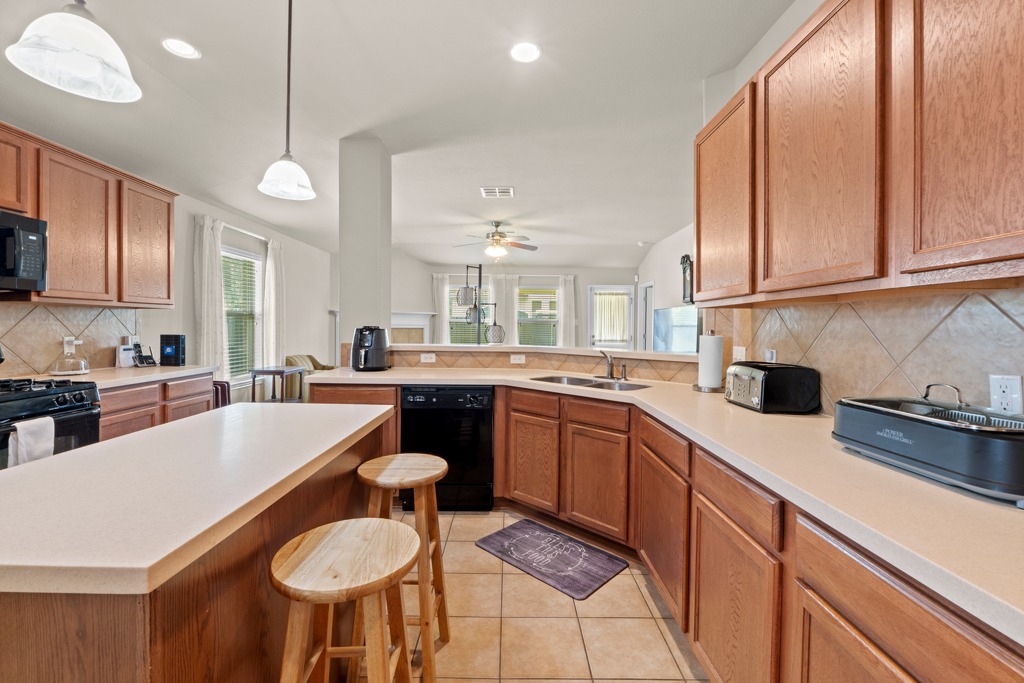 12008 Lansdowne Road Austin, TX 78754 - Photo 10 of 29 A well-appointed kitchen features warm wooden cabinetry, tiled floors, and a convenient breakfast bar.