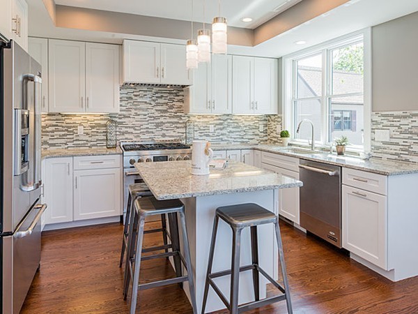 a kitchen with stainless steel appliances granite countertop wooden floor a sink a stove and white cabinets