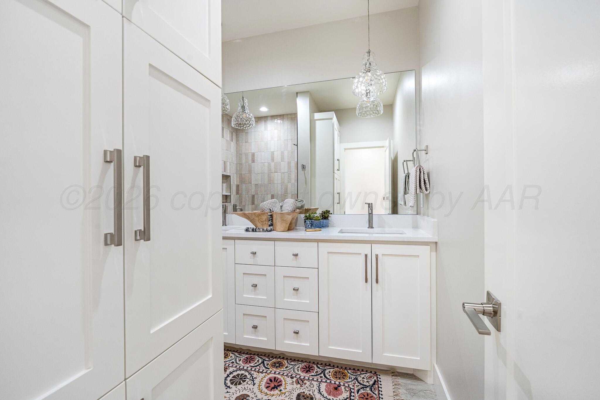 4000 Juniper Springs Road Amarillo, TX 79119 - Photo 34 of 40 a bathroom with a double vanity sink a mirror a bathtub and shower