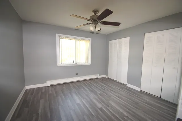 an empty room with wooden floor fan and windows