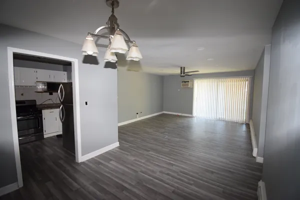 a view of a room with wooden floor a ceiling fan and a bathroom