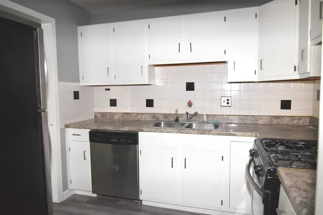 a kitchen with granite countertop a sink a stove and cabinets