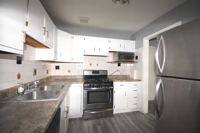 a kitchen with a refrigerator sink and white cabinets