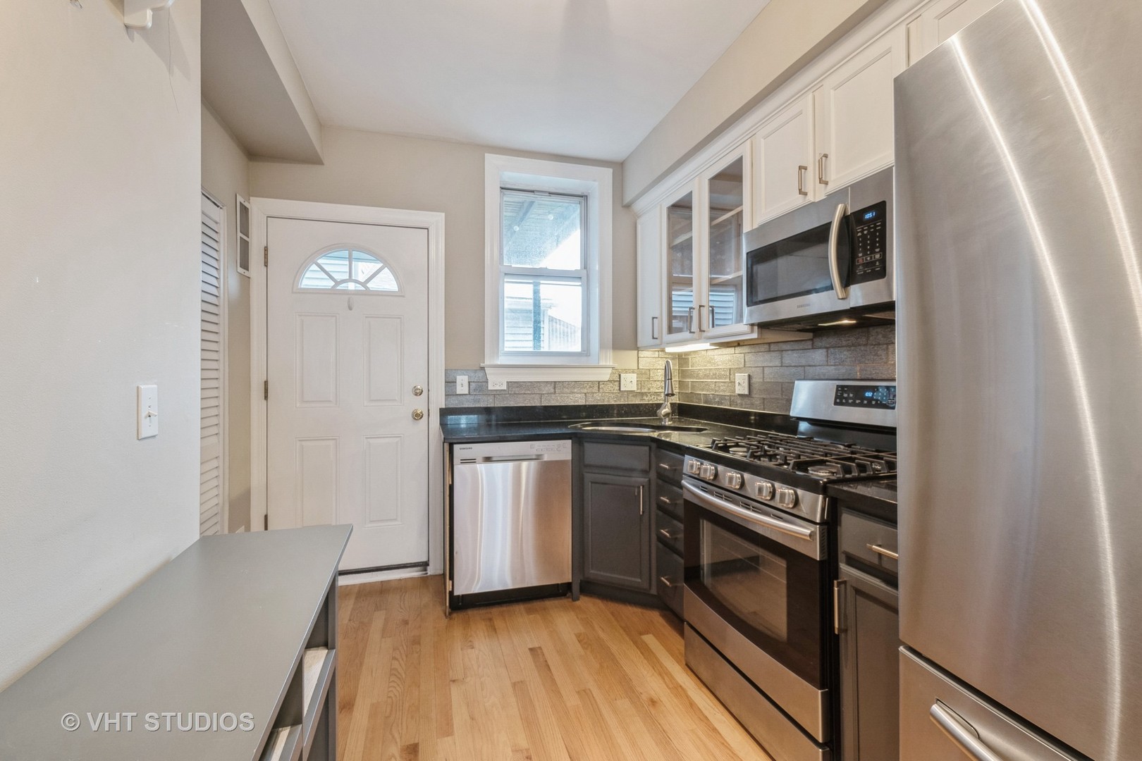 3337 West Byron Street, Unit 1 Chicago, IL 60618 - Photo 4 of 12 a kitchen with stainless steel appliances granite countertop a stove a sink and a microwave