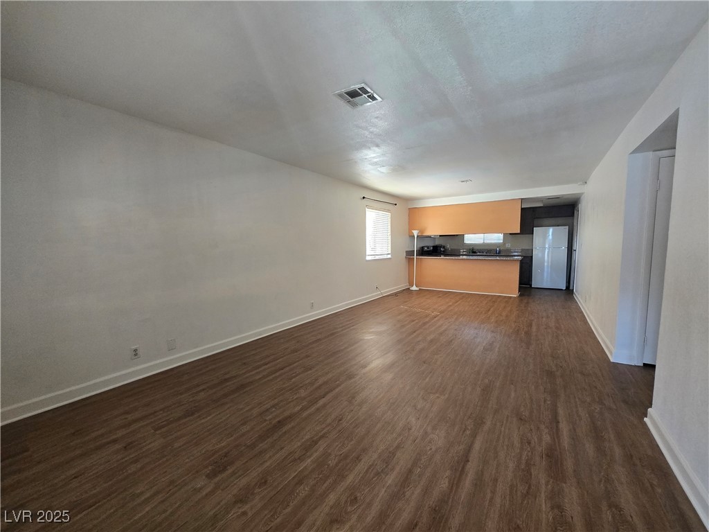 4440 Rich Drive, Unit C Las Vegas, NV 89102 - Photo 3 of 15 Unfurnished living room featuring dark wood-style flooring and baseboards