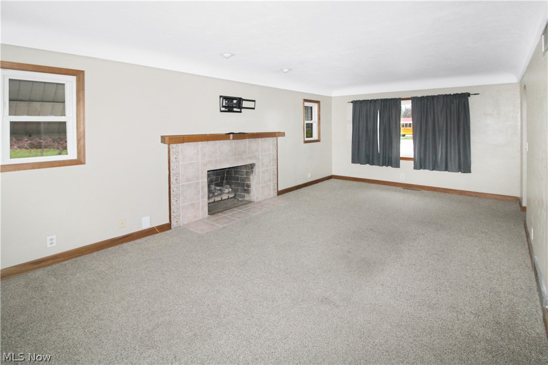 1036 West Fremont Road Port Clinton, OH 43452 - Photo 10 of 32 Unfurnished living room with a tile fireplace and light colored carpet