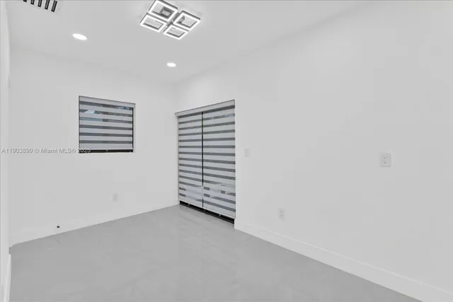 a large white kitchen with a large counter top a stove and a chandelier