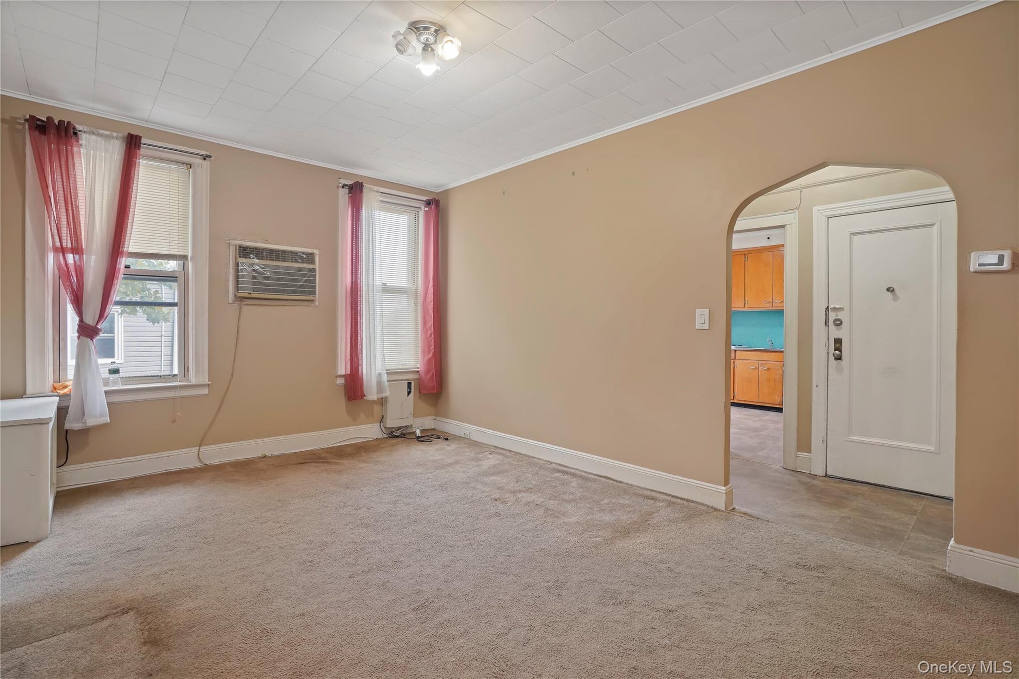 72-07 73rd Street Queens, NY 11385 - Photo 17 of 44 Unfurnished room featuring light carpet, arched walkways, crown molding, and a wall unit AC