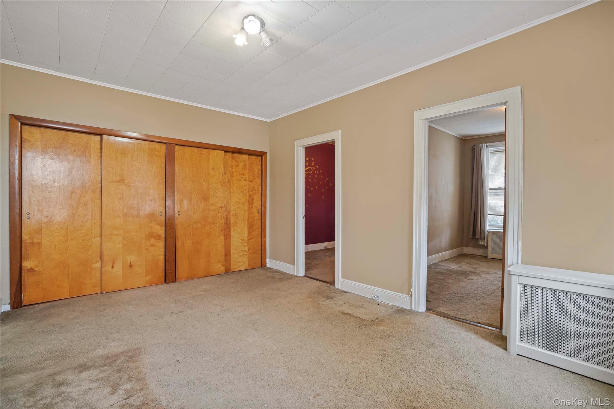 72-07 73rd Street Queens, NY 11385 - Photo 19 of 44 Unfurnished bedroom with radiator heating unit, a closet, carpet floors, and ornamental molding