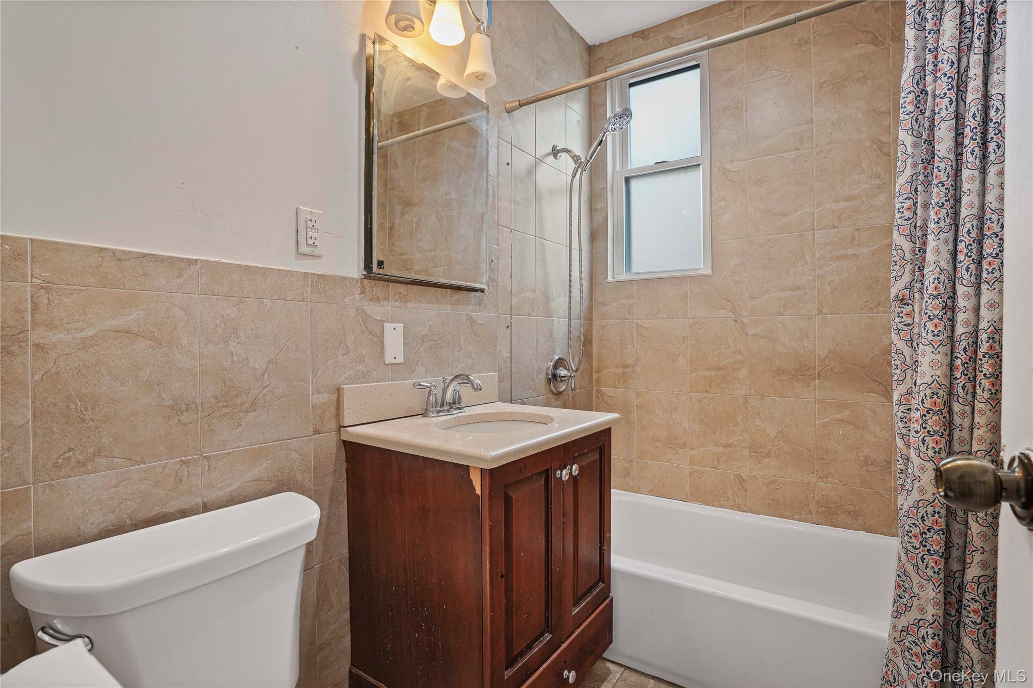 72-07 73rd Street Queens, NY 11385 - Photo 21 of 44 Bathroom with shower / tub combo, vanity, and tile walls