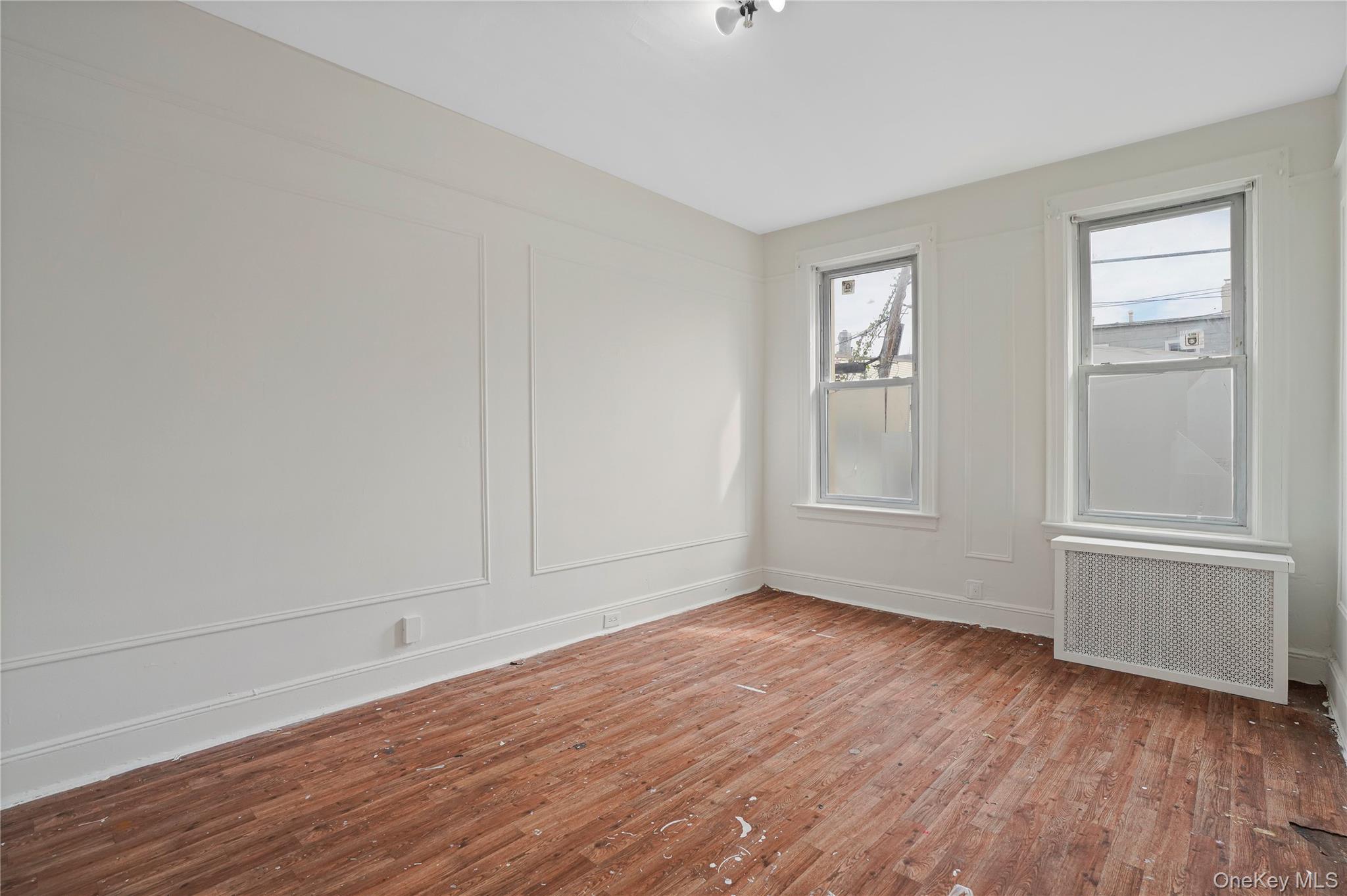 72-07 73rd Street Queens, NY 11385 - Photo 22 of 44 Unfurnished room with radiator, wood finished floors, and a decorative wall