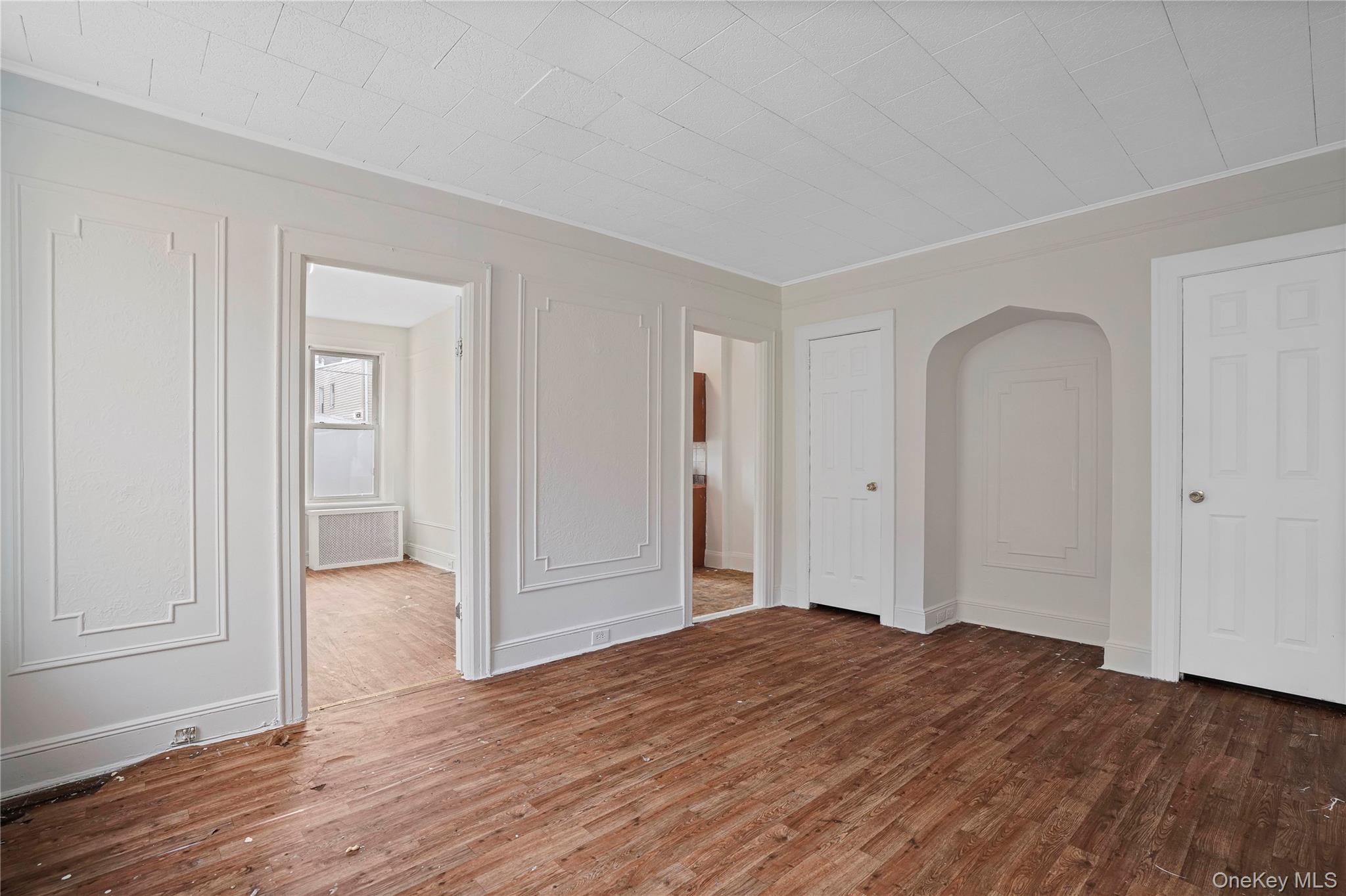 72-07 73rd Street Queens, NY 11385 - Photo 48 of 49 Unfurnished bedroom featuring wood finished floors, arched walkways, radiator, and crown molding