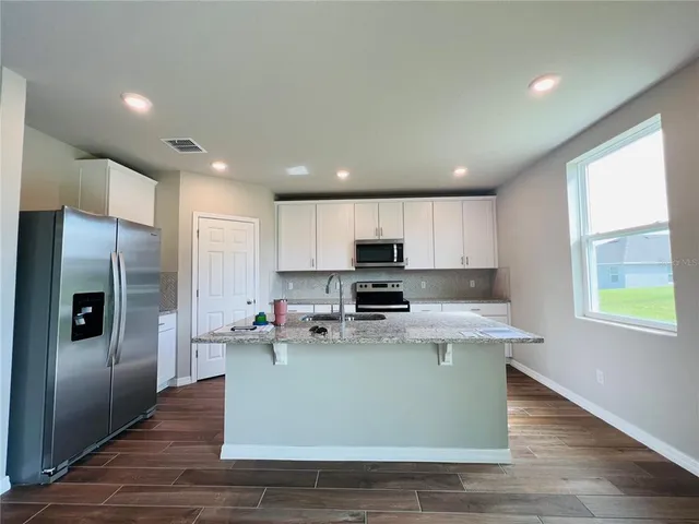 a kitchen with kitchen island a refrigerator sink and stove