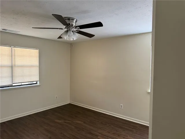 an empty room with wooden floor fan and windows