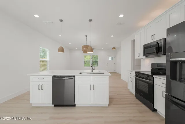 a kitchen with kitchen island granite countertop a sink appliances and cabinets