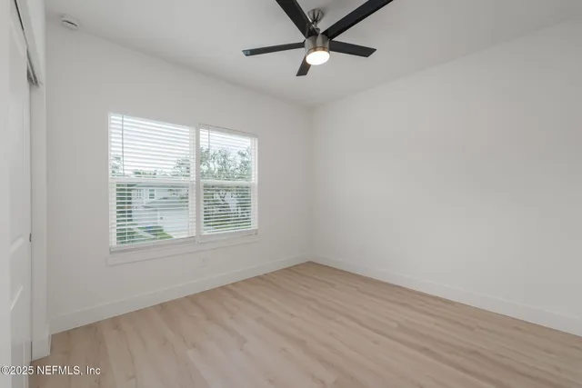 a view of empty room with wooden floor and fan