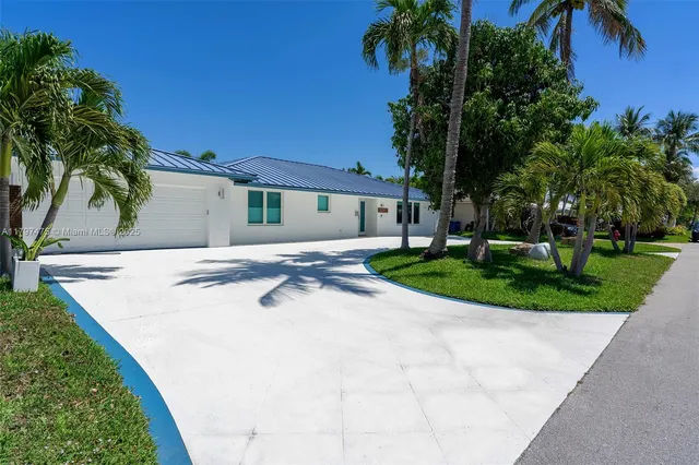 a view of a white house with a yard and palm trees