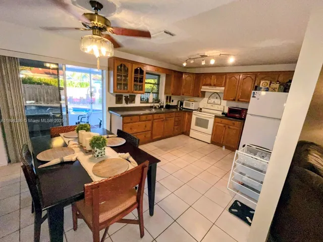 a kitchen with sink refrigerator dining table and chairs
