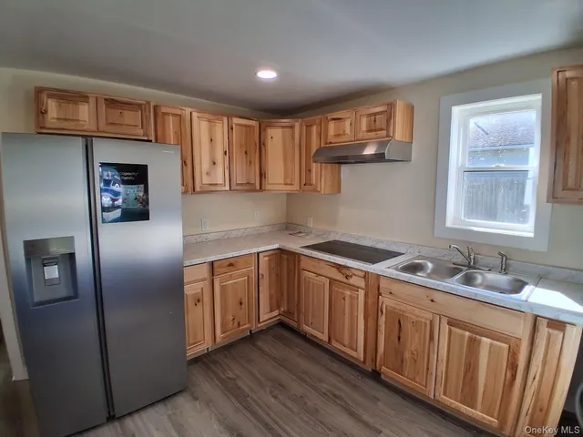 a kitchen with stainless steel appliances granite countertop a refrigerator a sink dishwasher a stove and white countertops with wooden floor