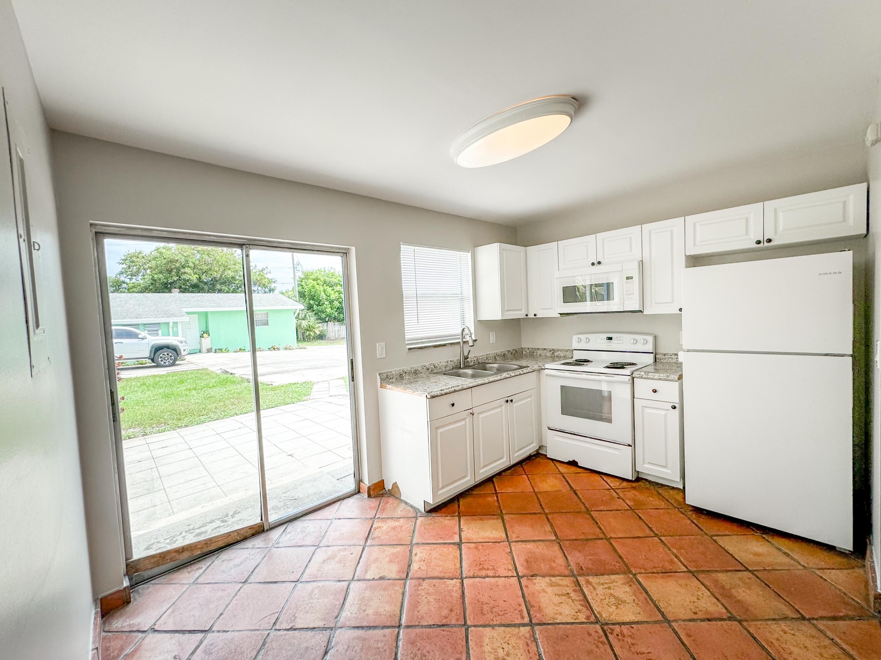 2735 Richard Road, Unit A West Palm Beach, FL 33403 - Photo 5 of 14 a kitchen with a refrigerator a stove top oven and white cabinets with island