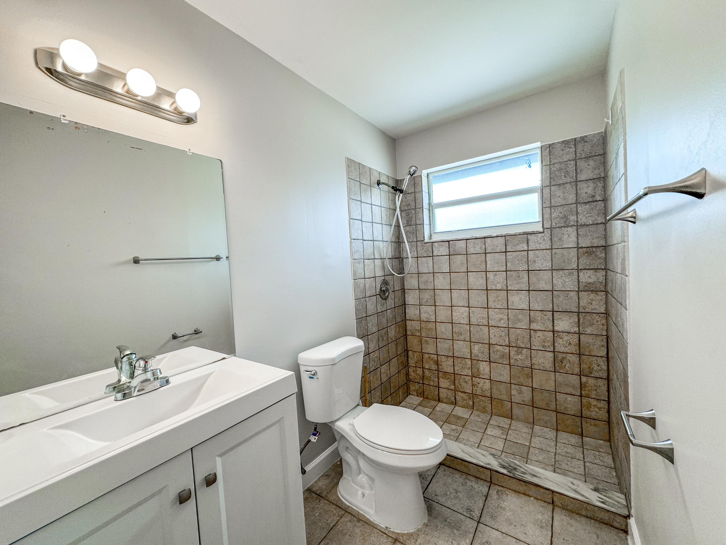 2735 Richard Road, Unit A West Palm Beach, FL 33403 - Photo 9 of 14 a bathroom with a sink a toilet and shower