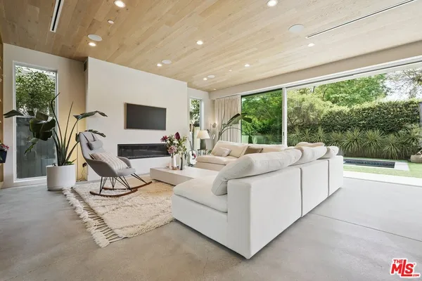 a living room with furniture a flat screen tv and a large window