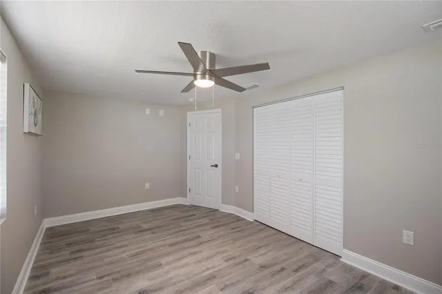 a view of empty room with wooden floor and fan