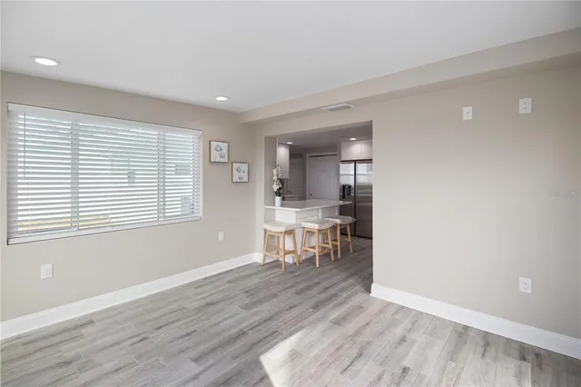 a view of an empty room with wooden floor and a ceiling fan