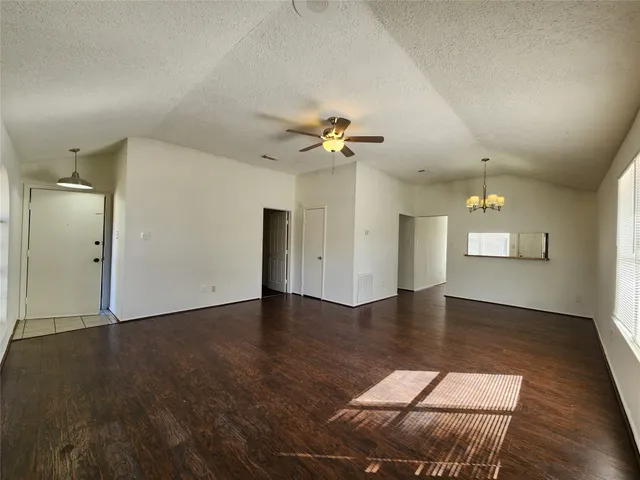 an empty room with wooden floor and ceiling fan