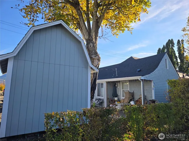 a view of a house with a yard plants and large tree