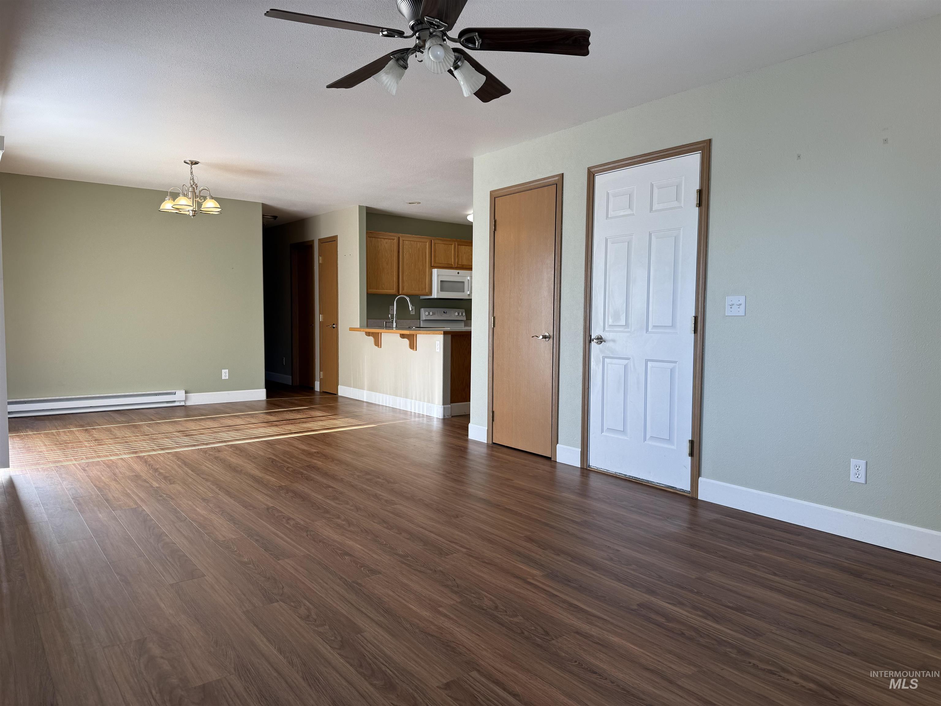 257 Pintail Lane Moscow, ID 83843 - Photo 3 of 28 Unfurnished living room featuring hanging lights, ceiling fan, dark wood-type flooring, and baseboard heating
