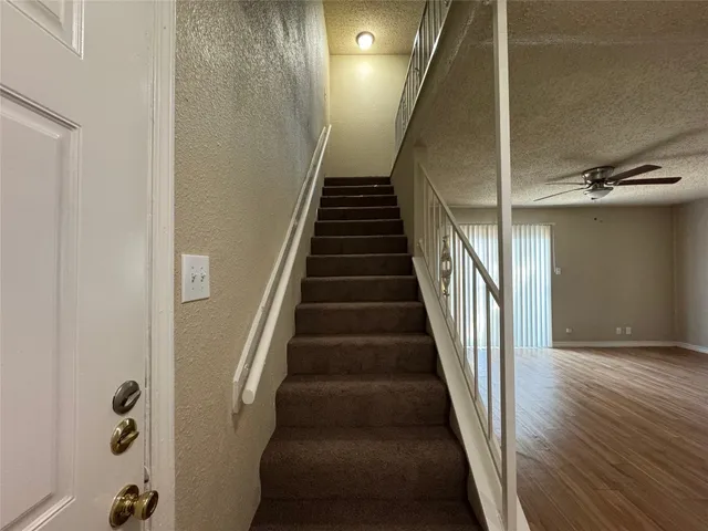a view of staircase with wooden floor and lots of frames on wall