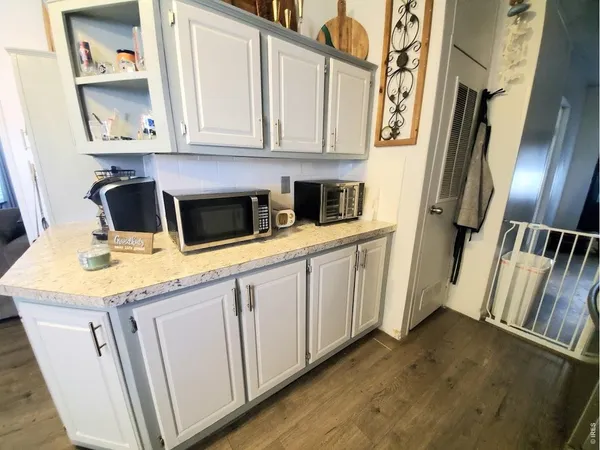 a kitchen with stainless steel appliances granite countertop a refrigerator a stove and white cabinets with wooden floor