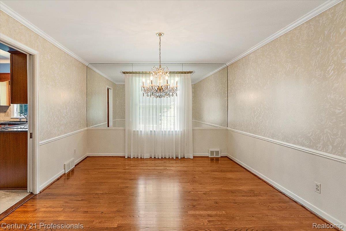 633 Foxhall Road Bloomfield Hills, MI 48304 - Photo 26 of 61 Hardwood flooring throughout the room with a crystal chandelier and full-height mirrored wall