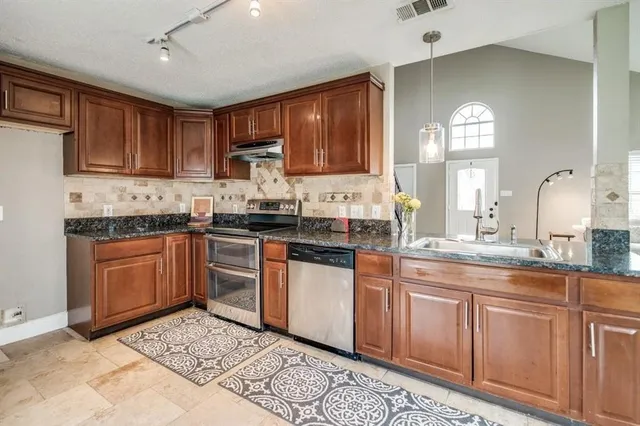 a kitchen with granite countertop stainless steel appliances sink stove microwave and cabinets