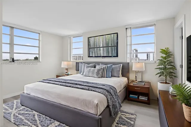 a bedroom with a large bed and a window with potted plants