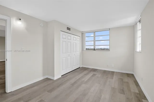 an empty room with wooden floor and windows
